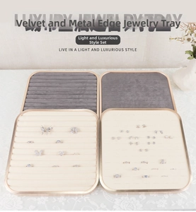 Flat lay of square metal jewelry display trays in beige and grey velvet for rings