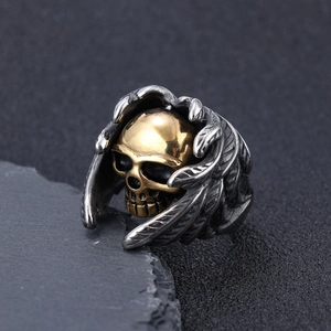 Gros plan d'une bague punk gothique avec crâne doré et détails de plumes argentées