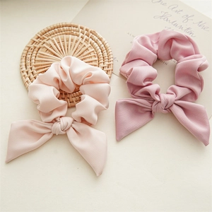 Close-up of pink and lotus pink satin bow scrunchies with elegant silk texture