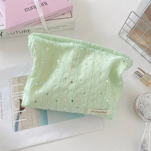 Vue détaillée d'une trousse à maquillage vert clair en dentelle avec sequins argentés