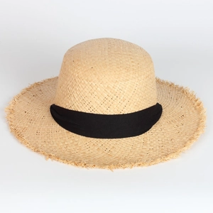 Detail of handmade raffia sun hat featuring a black ribbon bow and frayed edge texture