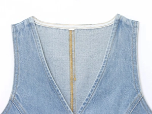 Détail du gilet en jean bleu clair avec col en V et finitions de coutures jaunes