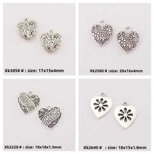 Macro detail of four heart-shaped antique silver charms with MOM text and floral patterns