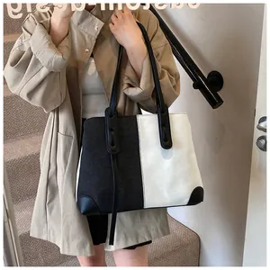 Close-up of contrast black and white denim tote bag with leather handles on a model