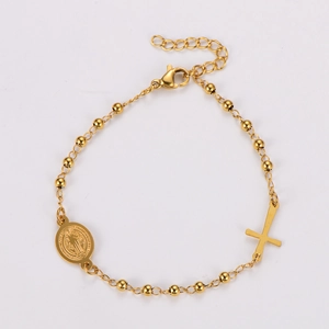 Detail of gold beaded bracelet featuring cross and Saint Benedict coin charms with clasp