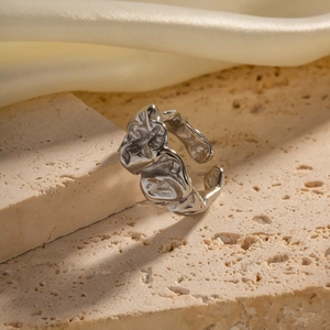 Modern minimalist silver lava-textured stainless steel ring on elegant beige stone base