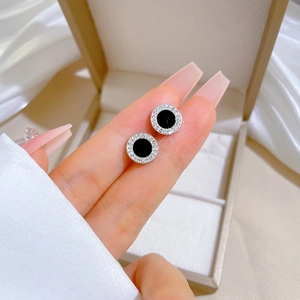 Detail of round titanium steel stud earrings with black enamel center and zircon border