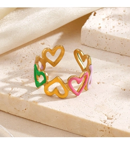 Detailed macro view of gold heart rings with colorful enamel inlay on stone surface