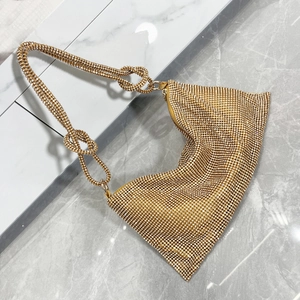 Detail of golden rhinestone hobo bag showing the double knot handle design and sparkling crystals