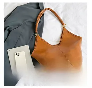 Detail view of brown leather tote showing capacity with iPad and pleated handle rings