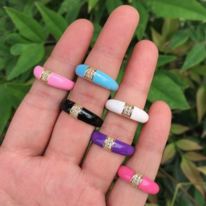 Detail of six colorful enamel rings with gold plating and sparkling zircon inlay on hand