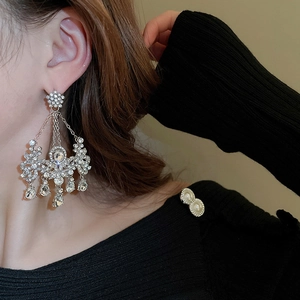 Détail de boucles d'oreilles pendantes argentées avec cristaux sur un mannequin