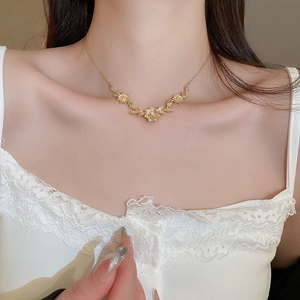 Close-up of a gold flower pendant necklace with white zircons on a female neck