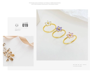 Detail shot of three golden flower rings with white, purple, and pink gemstones