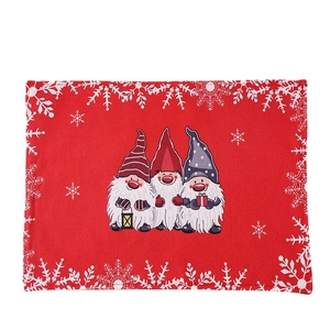 Christmas table mat featuring three festive gnomes and white snowflakes on red linen