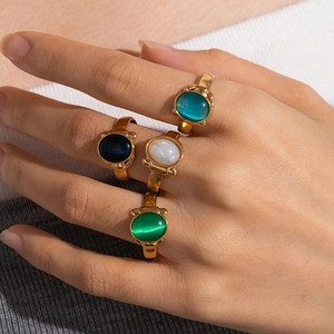 Detailed close-up of retro gold-plated rings with colorful natural stone inlays on finger