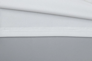 Gros plan du tissu en maille côtelée blanche montrant les détails de couture à double aiguille