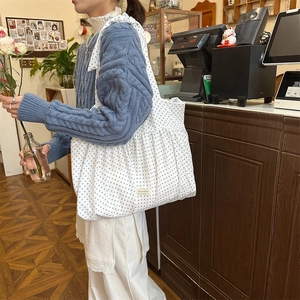 Detail der weißen Plissee-Stofftasche mit blauen Punkten und seitlicher Schleife