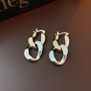 Detail of two-tone gold and silver linked geometric drop earrings on leather surface