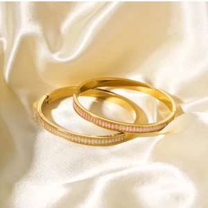 Detailed view of gold and rose gold bangles with zircon inlay on champagne silk fabric