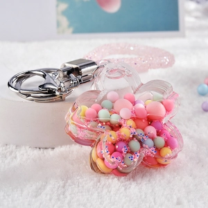 Detail of flower-shaped acrylic liquid keychain with macaron beads and pink glitter strap