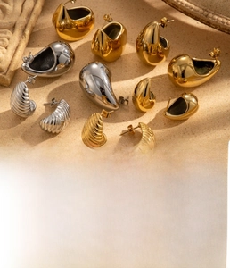 Detail of chunky C-shape drop earrings in gold and steel finish with water ripple texture
