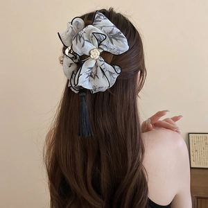 Détail d'une élégante pince à cheveux avec nœud en peinture à l'encre et pompons