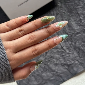 Emerald green marble press-on nails with 3D floral reliefs and golden star accents