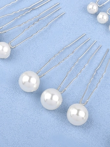 Detailed view of white pearl hair pins with U-shaped silver metal forks for bridal styling