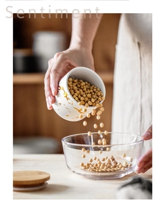 Action shot of soy beans pouring from a marble pattern ceramic storage jar into a glass bowl