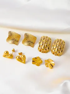 Detail of four pairs of vintage gold earrings on white silk featuring square and heart shapes