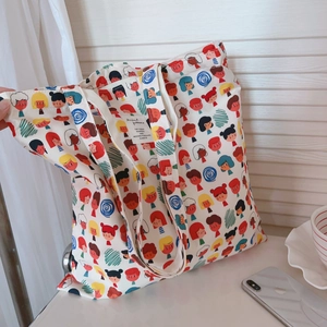 Détail d'un sac cabas en toile blanche avec imprimés cartoons colorés et étiquette