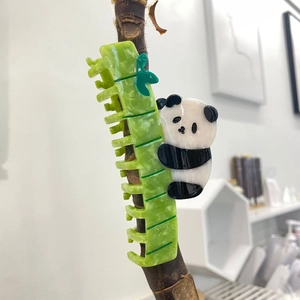 Detail of panda and green bamboo claw clip on branch made from glossy acetate material