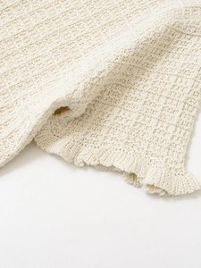 Macro detail of creamy white waffle knit fabric with elegant wavy pleated edges