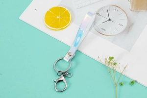 Detail view of colorful laser PVC lanyard keychain with metal ring on marble surface