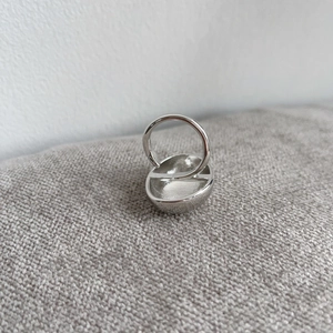 Close-up of a silver-toned minimalist ring with smooth concave texture and vintage style