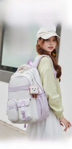 Detail of white and purple school backpack with multi-pocket design and cute plush charm