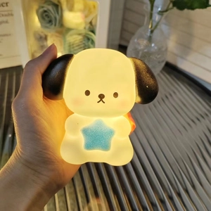Detail shot of a hand holding the glowing Pochacco cartoon night light with blue star