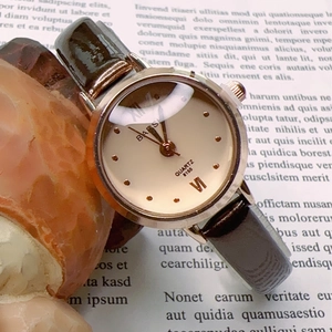 Close-up of elegant small dial women's quartz watch with brown leather strap on a book