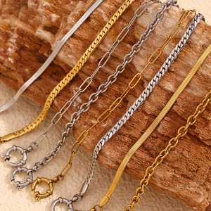 Dettaglio di catene serpente, cubane e a graffetta in oro 18K e argento su legno
