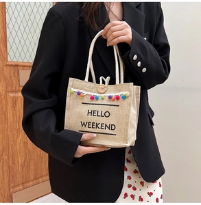 Detail of linen tote bag featuring 'Hello Weekend' print, lace trim and wood button