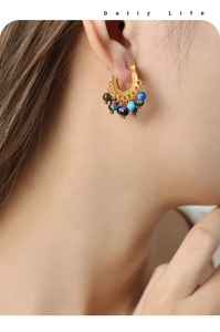 Détail de boucles d'oreilles dorées avec perles d'agate colorées sur modèle au style élégant