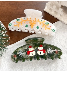 Detail von Weihnachts-Haarklammern mit Rentier- und Schneemann-Motiv auf festlichem Holz