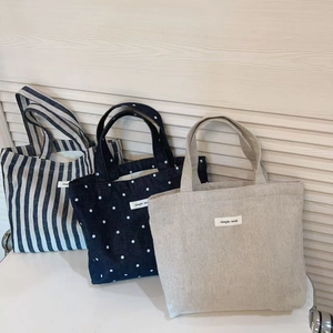Detailed shot of striped, polka dot, and solid canvas tote bags with simple wish labels