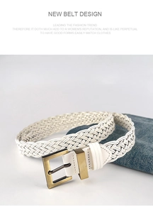 Close-up of white woven belt with gold metal buckle resting on blue denim jeans