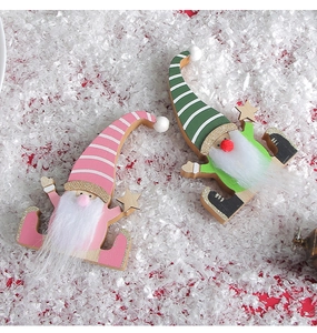 Close-up of pink and green striped wooden Christmas gnomes on white snow background