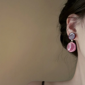 Close-up of translucent resin drop earrings with contrasting purple and red tones