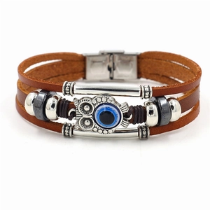 Detail of multi-layer leather bracelet featuring owl motif and blue evil eye charm