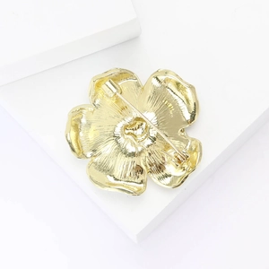 Detailed macro view of gold flower brooch showing fine petal texture and metal back pin