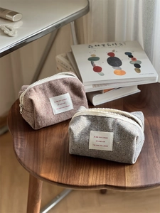 Detailed texture of herringbone fabric pouches with chunky white zippers on wooden table